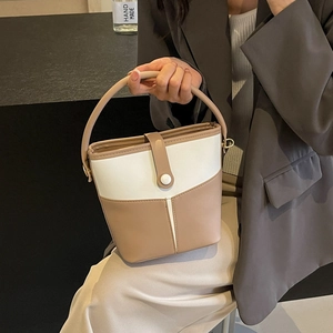 Minimalist beige and khaki patchwork bucket bag with top handle and gold hardware