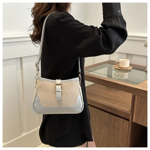 Silver leather trim detail on beige canvas shoulder bag worn by model in a cafe