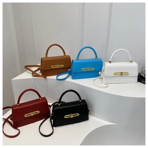 Detail view of stylish square handbags in five colors with sleek gold metal bar clasps