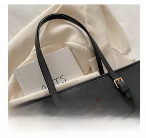 Dettaglio borsa tote in pelle Saffiano nera con logo dorato e finiture in metallo lucido