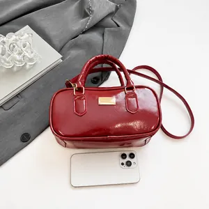 Détail du sac à main en cuir verni bordeaux avec un smartphone pour comparer la taille