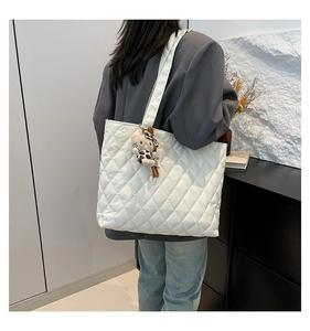 White quilted tote bag with spacious interior and cute plush charm detail shown on model