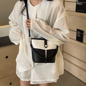 Minimalist black and white color-block bucket bag with shoulder strap and metal hardware