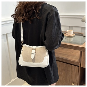Detail of contrast stitching and beige canvas texture on retro crossbody bag with gold buckle