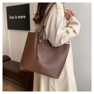 Detail view of brown faux leather tote bag with stylish black and white woven rope charm