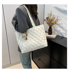 White quilted puffer tote bag detail with leopard cat plush charm and modern interior setting