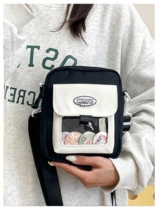 Détail du sac ita bandoulière avec fenêtre transparente montrant des badges de dessin animé