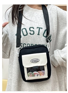 Vue détaillée du sac ita avec fenêtre transparente, badges de dessin animé et bandoulière large