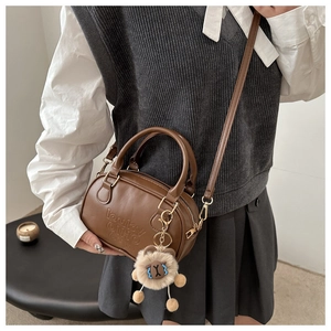 Détail du petit sac Boston marron avec breloque lion en peluche et logo embossé