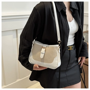 Detail of canvas and leather patchwork shoulder bag with metal buckle on model