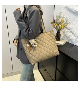 Detail of khaki quilted tote bag with diamond pattern and a cute leopard cat plush charm