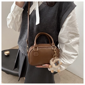 Détail du sac à main en cuir marron avec gravure LUCKY et breloque en peluche douce