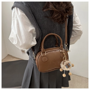 Gros plan du sac vintage en cuir marron avec logo embossé et breloque lion en peluche