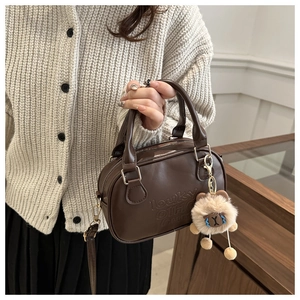 Gros plan d'un mini sac carré en cuir marron rétro avec gaufrage et porte-clé peluche
