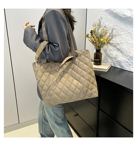 Detail view of large quilted tote bag in beige shown on model for daily commuting style