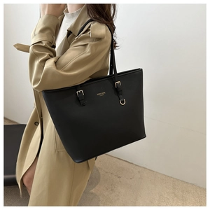 Dettaglio della borsa tote in pelle nera con logo dorato e tracolla regolabile fine
