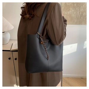 Detail of black retro bucket bag with decorative woven rope and golden bell charm