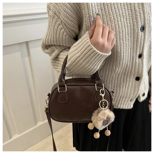 Détail du sac en similicuir marron avec lettres gaufrées et breloque mouton en peluche