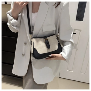 Detail of retro contrasting canvas bag with leather trim and gold buckle on model