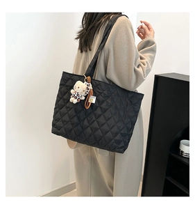 Detailed back view of a black quilted tote bag with a leopard print plush cat charm