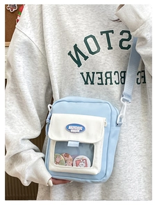 Détail du sac à bandoulière bleu clair avec fenêtre PVC et épingles de dessin animé décoratives