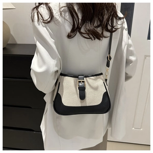 Retro cream canvas crossbody bag with black leather trim and gold buckle shown on a model