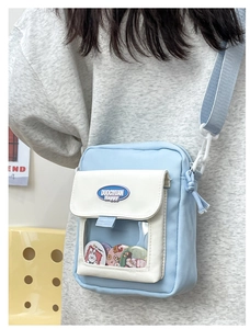 Détail du sac bandoulière en toile bleu et blanc avec fenêtre PVC et badges mignons