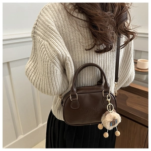 Gros plan sur un sac Boston vintage en cuir marron avec logo embossé et charm de mouton