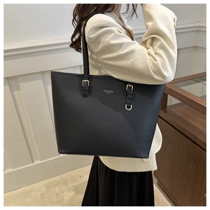 Dettaglio della borsa shopper nera con trama in pelle e fibbie metalliche dorate