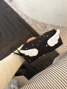 Close-up of black star-patterned pencil case featuring white plush wings and carry strap