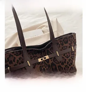 Détail du cabas imprimé léopard avec bandoulières en cuir marron et boucle dorée