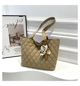 Detail of khaki quilted tote bag with soft texture and cute kitten plush charm