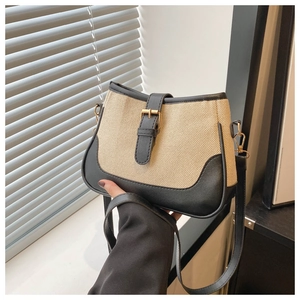 Detail of contrast stitching woven bag with black leather trim and gold buckle accent