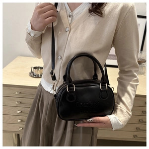 Détail d'un mini sac Boston vintage en cuir noir avec gaufrage et bandoulière réglable