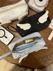 Detailed view of star print stationery bags with plush angel wings on a wooden desk