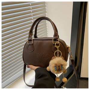 Détail d'un sac à main vintage en cuir marron avec gaufrage et porte-clé en peluche