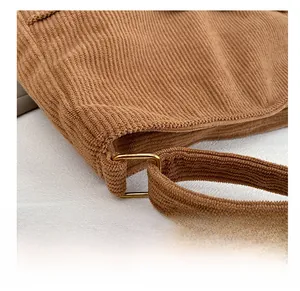 Macro detail of brown corduroy tote bag featuring premium golden metal connection rings