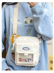 Détail du sac bandoulière en toile blanche avec fenêtre transparente et badges de dessin animé