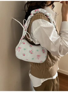 Close-up of white drawstring shoulder bag with floral print and pleated texture fabric
