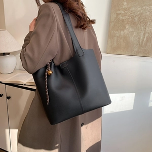 Minimalist black leather tote bag with gold bell charm for stylish daily commuting use