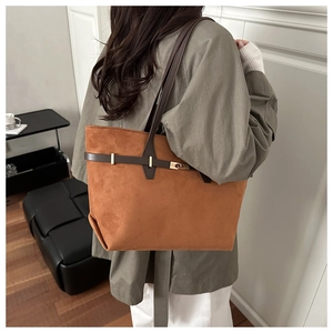 Sac fourre-tout en daim marron avec anses en cuir porté à l'épaule dans un intérieur