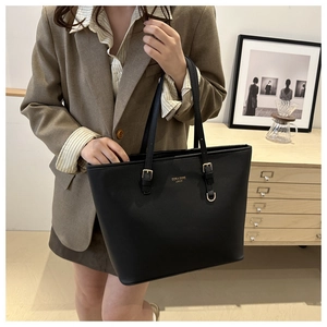 Dettaglio di una grande borsa tote nera con scritte dorate indossata da una modella