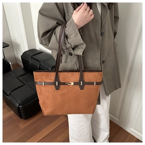 Sac cabas en daim marron avec anses en cuir porté à l'épaule dans un décor moderne