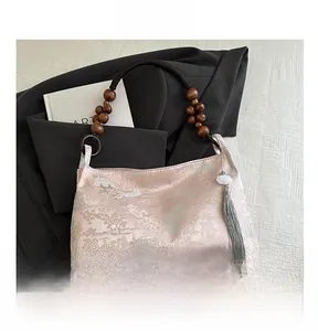 Detail of pink floral jacquard fabric with wooden bead handle and silk tassel accent