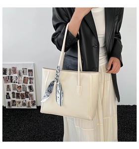 Detail of a creamy white lychee grain tote bag decorated with a blue printed silk scarf
