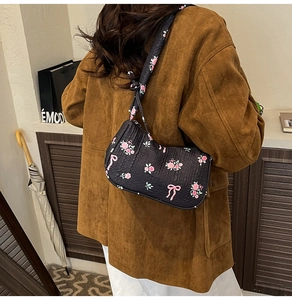 Detail of black quilted underarm bag featuring pink floral print and bow tie strap