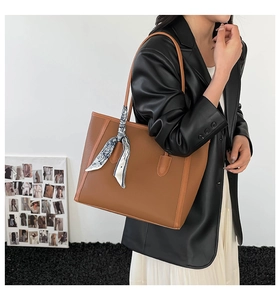 Brown lychee texture leather tote bag worn by model featuring stylish silk scarf detail