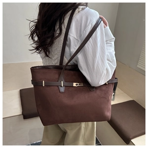 Détail du grand sac cabas en daim marron foncé avec boucle dorée porté par un mannequin