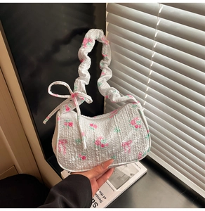 Close-up of white bubble pleated underarm bag with pink rose patterns and bow details