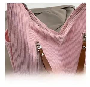 Detail of pink corduroy shoulder bag showing smooth silver zipper with brown leather puller